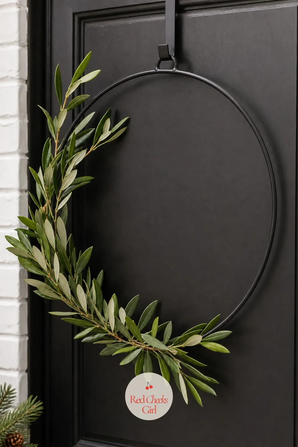 Geometric Metal Ring Olive Wreath — A plain black metal ring with a few sprigs of preserved olive branch wired loosely across one side. Christmas wreaths for
