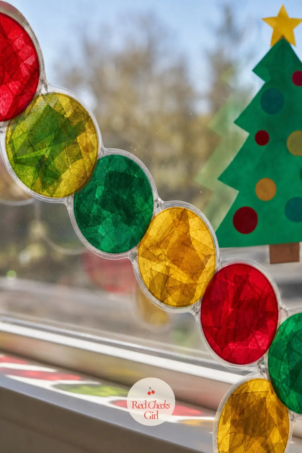 A Tissue Paper Stained Glass Chain Across the Window — Cut circles of ruby, emerald and gold tissue paper, sandwich them between two strips of clear contact