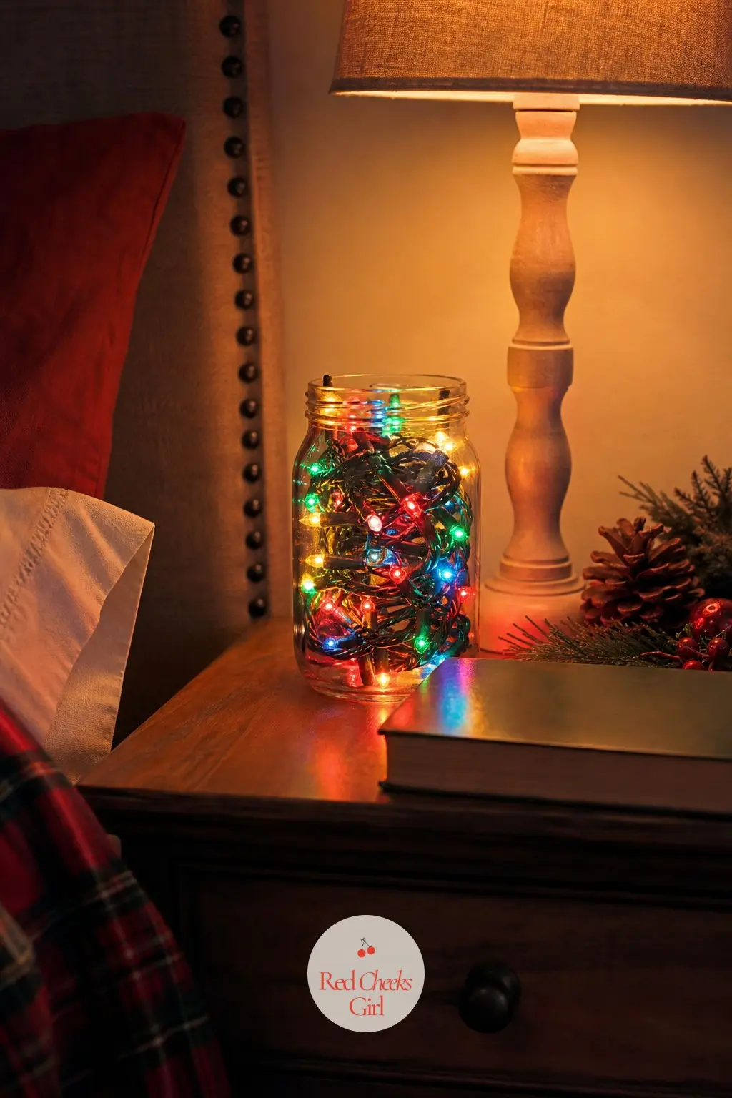 The Bedside Table, Lit by a Small Multicolor Light Strand — A short battery-powered multicolor light strand coiled in a small glass jar on the bedside table