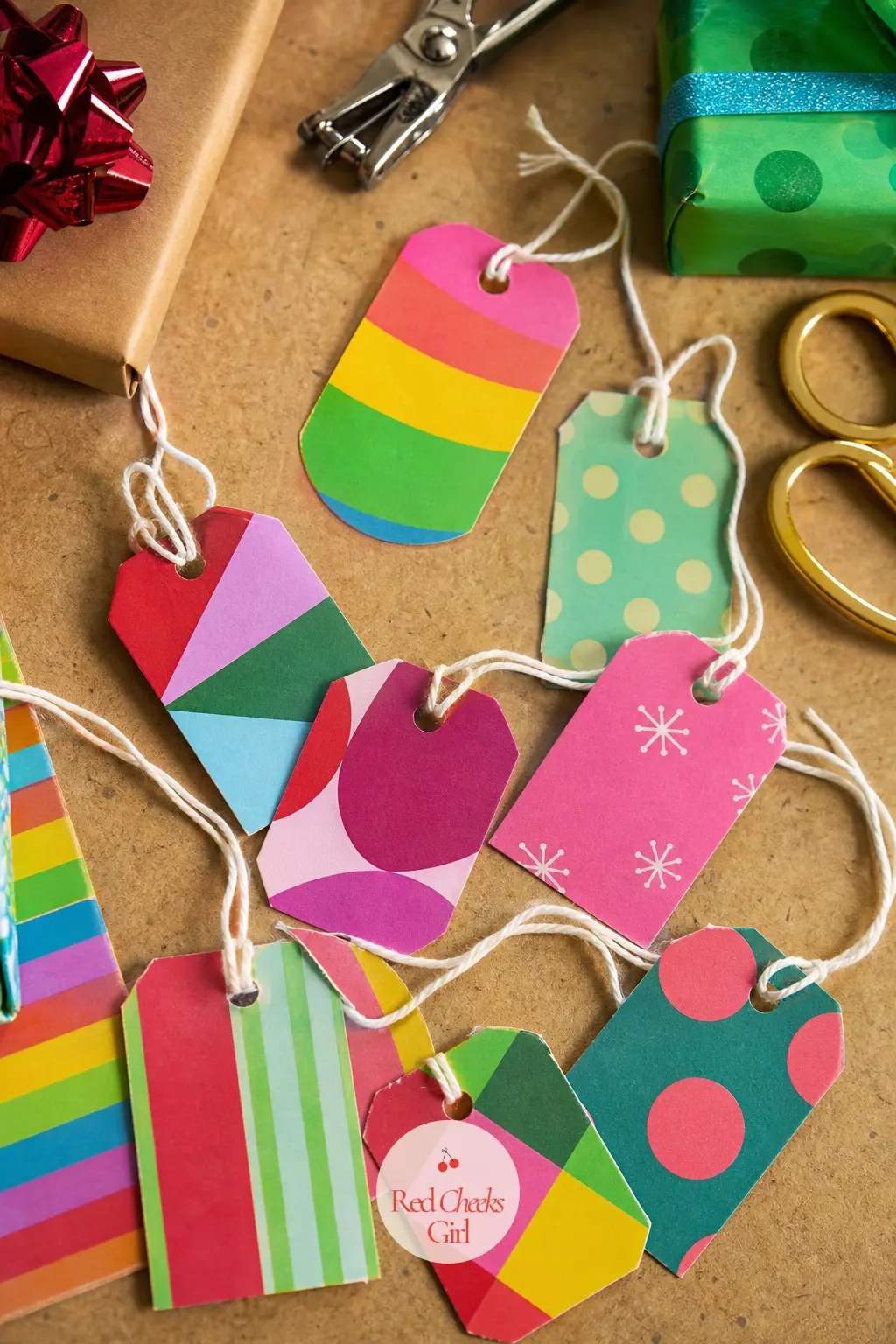 The Gift Tags, Cut From Leftover Rainbow Scraps — Scraps left over from the wrapping paper rolls get cut into simple tag shapes and threaded onto string, so no