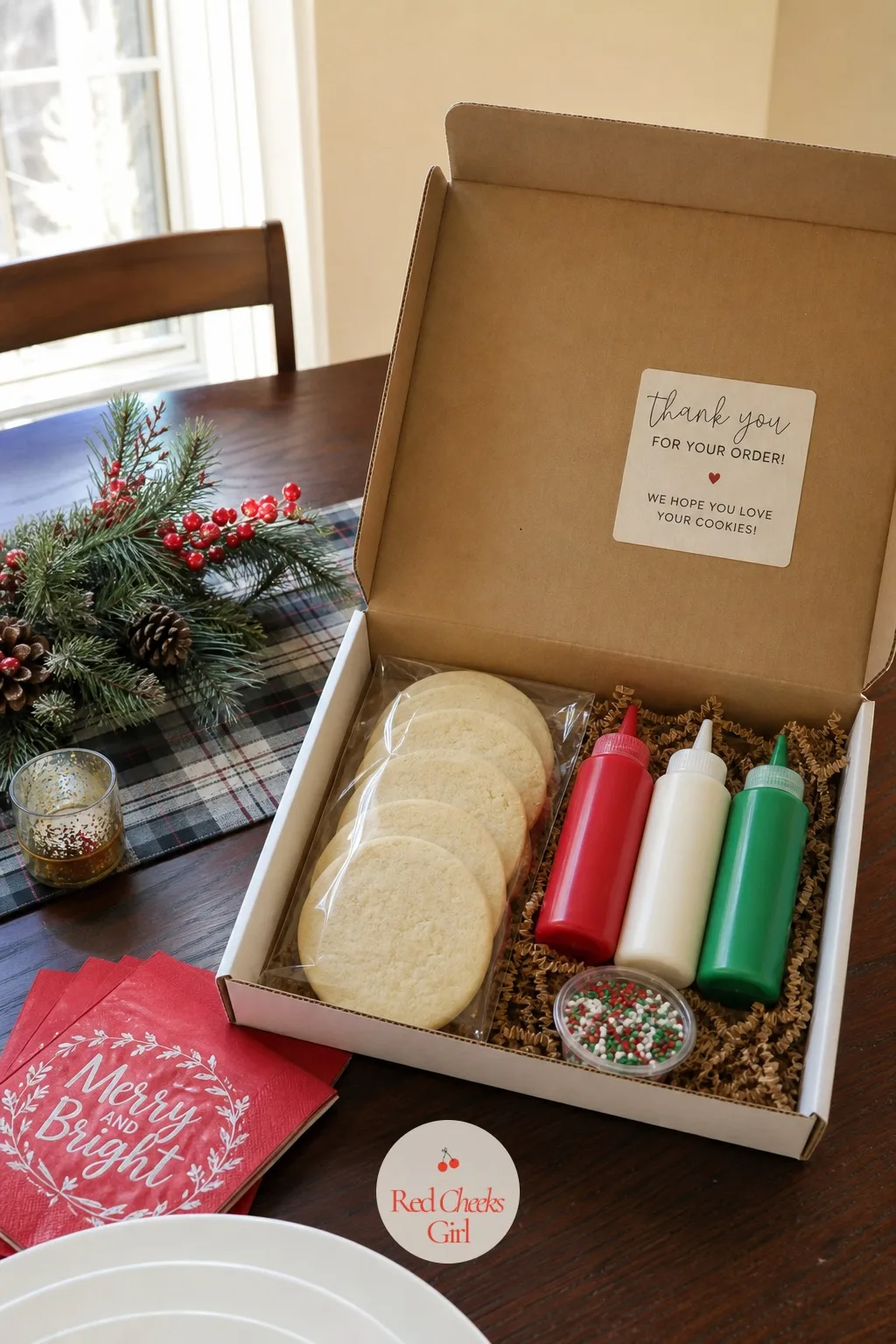 Cookie Decorating Kits to Ship — A flat kit box lies open showing plain round cookies, three small squeeze bottles of icing, and a scatter of sprinkles in a