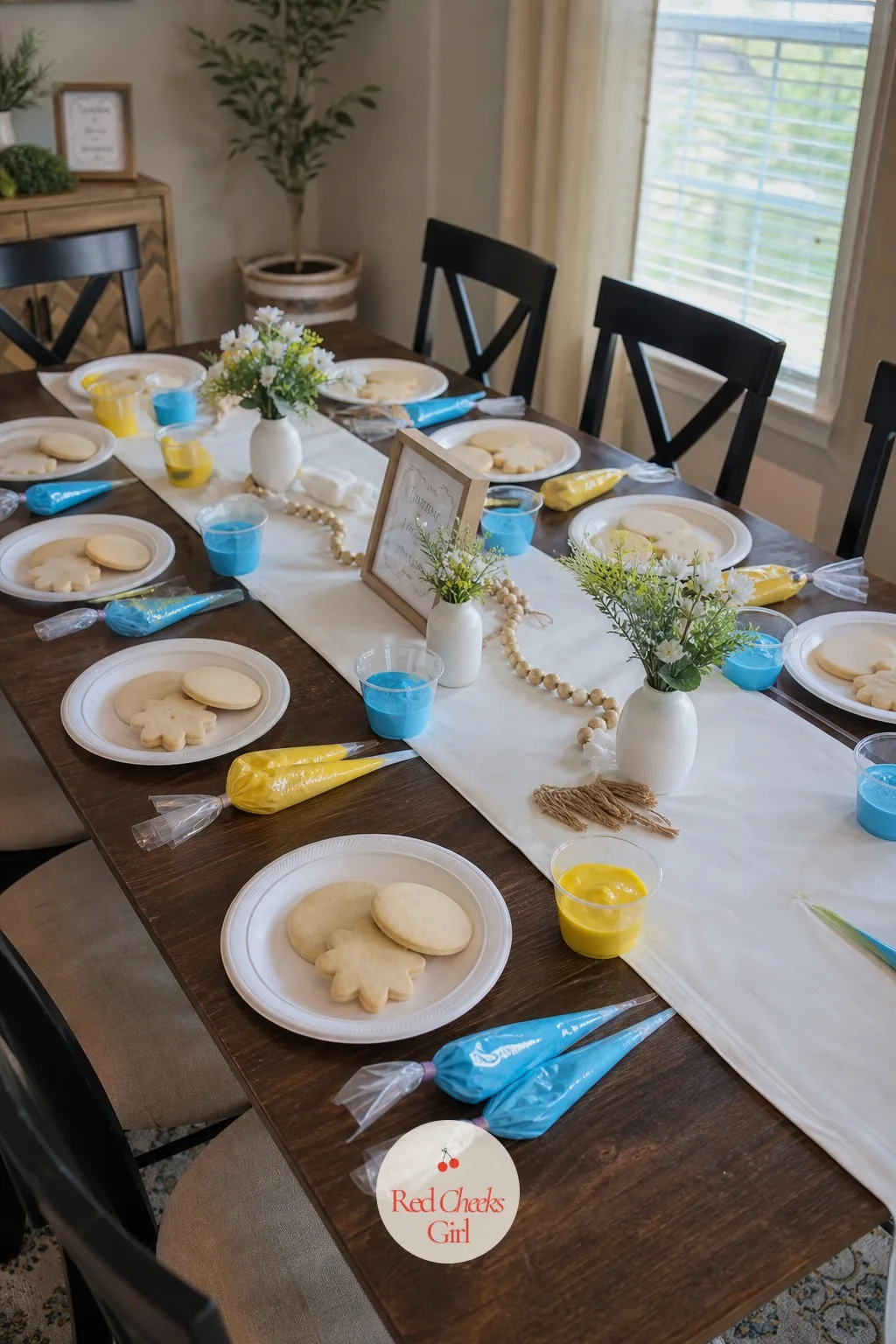In-Person Cookie Decorating Classes — A long table is set with plain cookies at each place, small cups of icing in two colors, and a piping bag resting beside