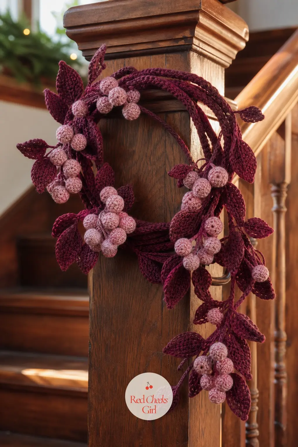 The Burgundy and Dusty Rose Berry Vine Wreath for the Staircase — A long crocheted vine in burgundy winds in a loose ring, with dusty rose berries trailing off