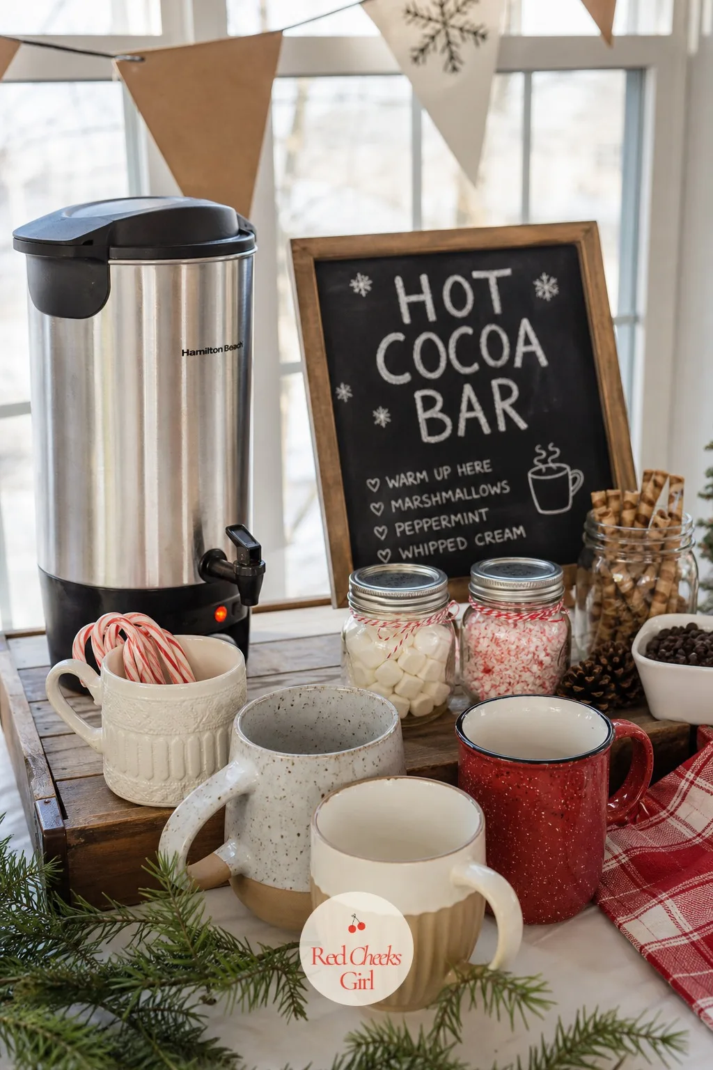 Hot Cocoa Bar — Built in layers, bottom to top: a wooden tray as the base, a large pot or urn of cocoa at the back, a row of mismatched mugs in front of it