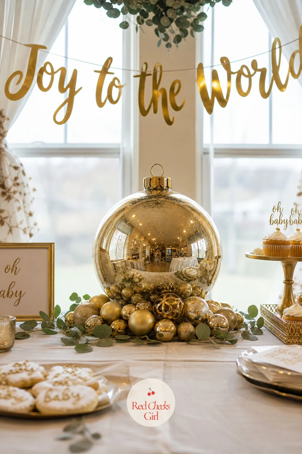 Joy to the World — Grand rather than cozy: a large glass globe ornament sits center table, gold script banner letters spell the phrase overhead, and a cluster