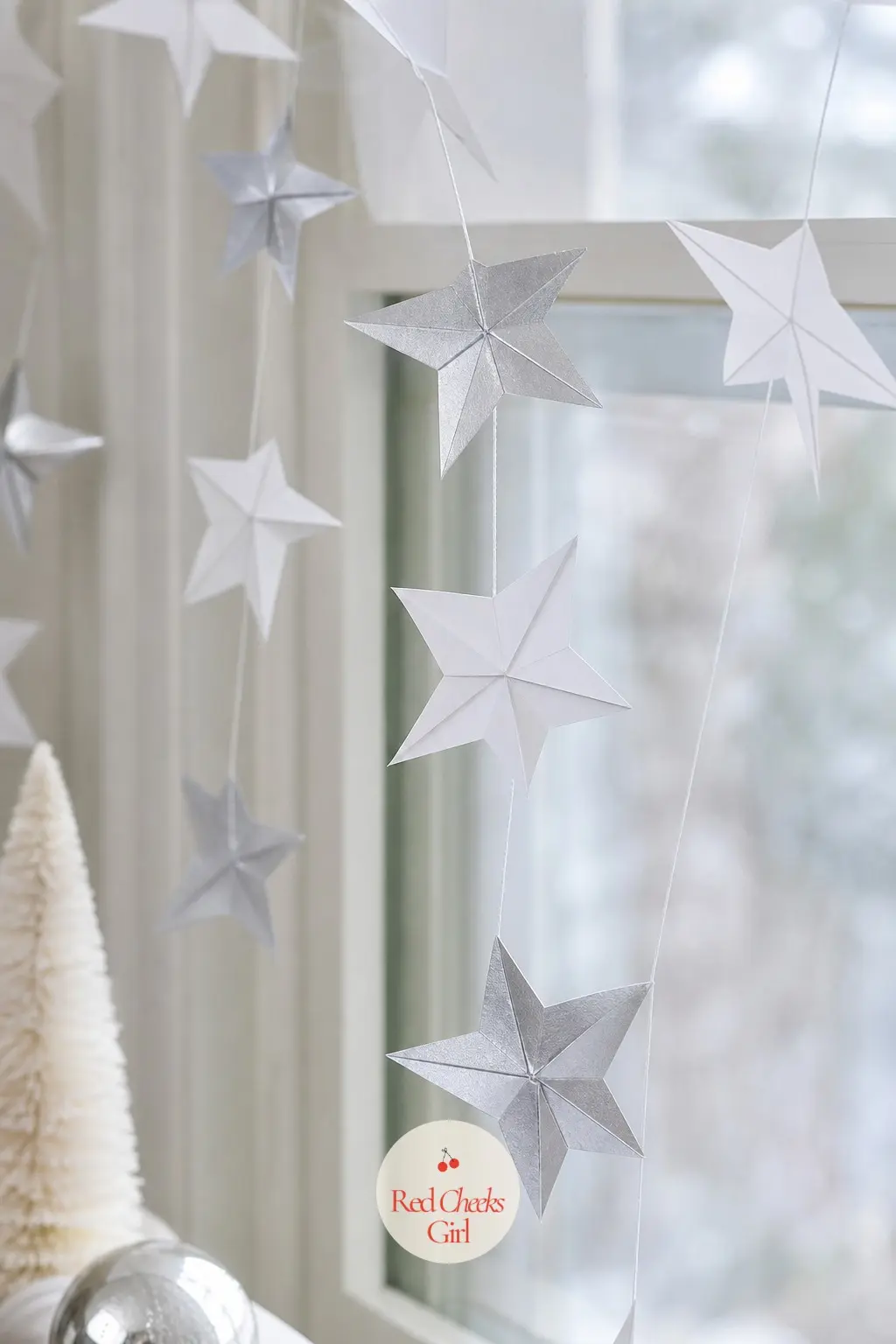 Folded Paper Stars Garland — Simple folded stars in white and silver cardstock thread onto clear fishing line for a garland that catches light without needing