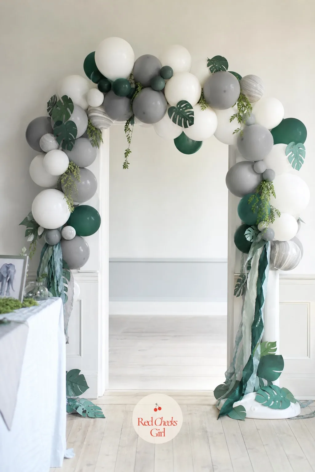 The Gray, White And Emerald Balloon Arch — An arch gives the room a frame to photograph through, which matters more than any single centerpiece once the party