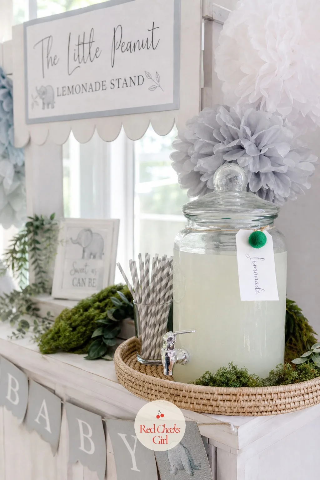The Little Peanut Lemonade Stand — Guests need somewhere to refill a glass that is not hovering near the gift table, and a labeled drink station solves that