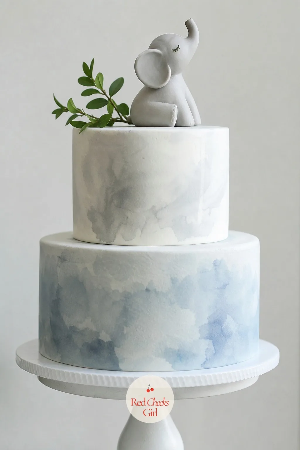 The Watercolor Cake With An Elephant Topper — This is the cake that makes the whole table look intentional rather than assembled in a hurry. Elephant baby