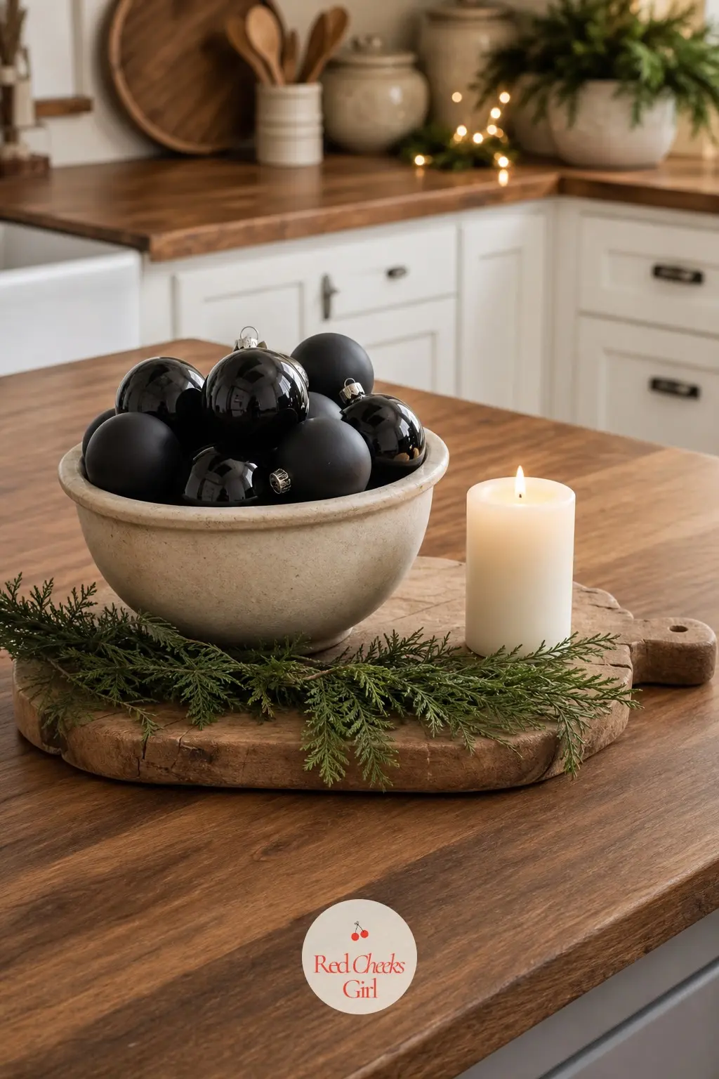 The Kitchen Island — The island is the kitchen's one chance at a centrepiece: a cream ceramic bowl filled with black bauble ornaments, set on a wood board