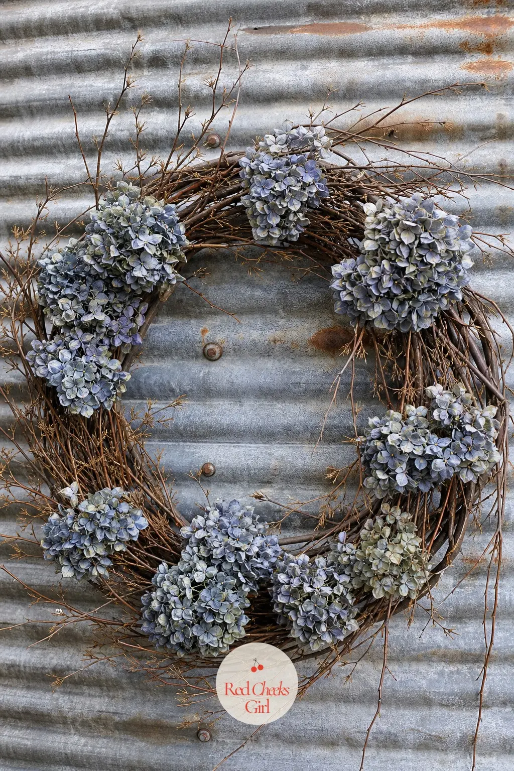 The Dried Hydrangea and Twig Wreath for the Grain Bin Wall — Dusty blue-grey dried hydrangea heads sit loose among bare brown twigs, the whole thing left