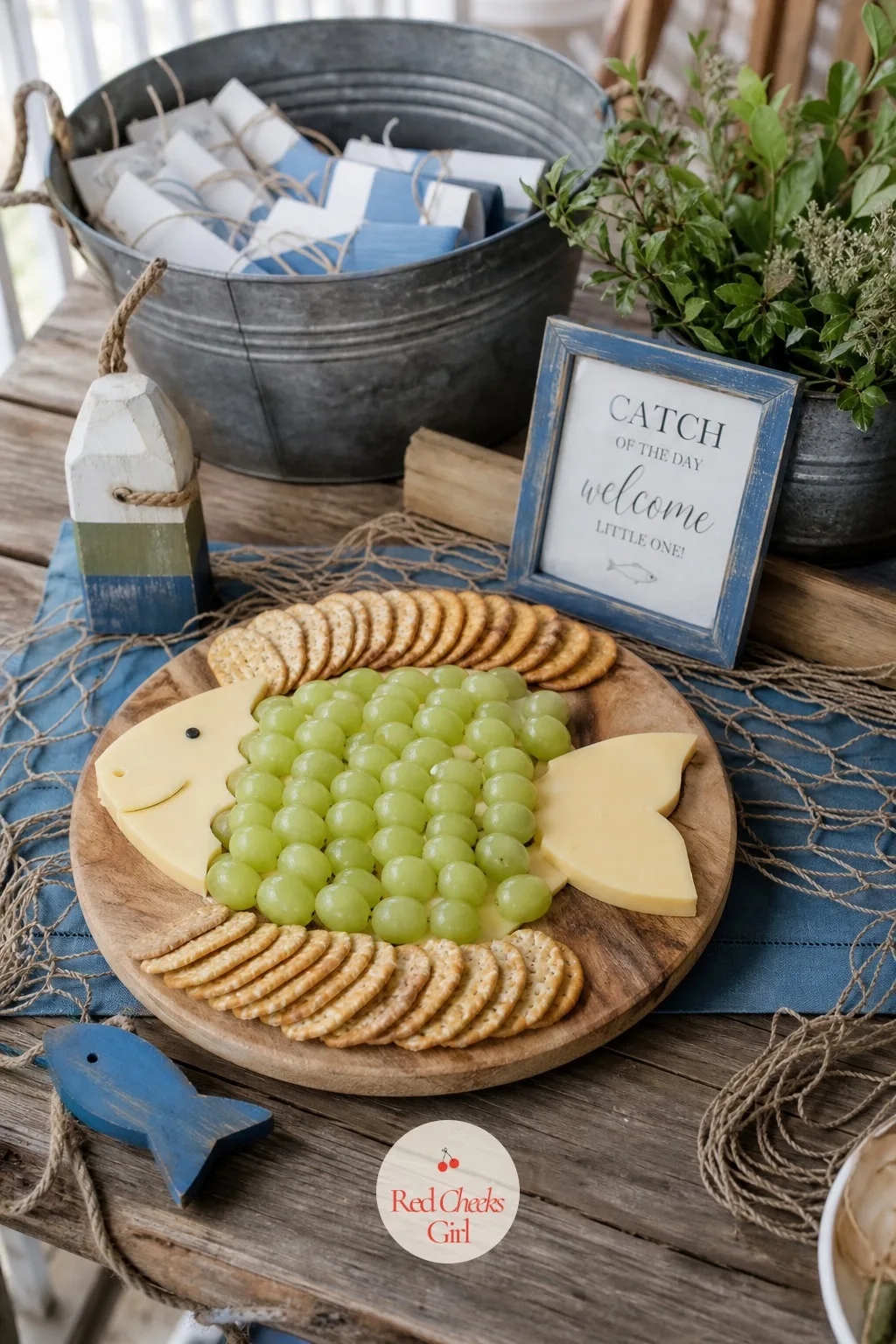 Catch of the Day Grazing Board — A wood board laid with cheese cut into fish shapes, grapes arranged in overlapping rows like scales, and crackers fanned