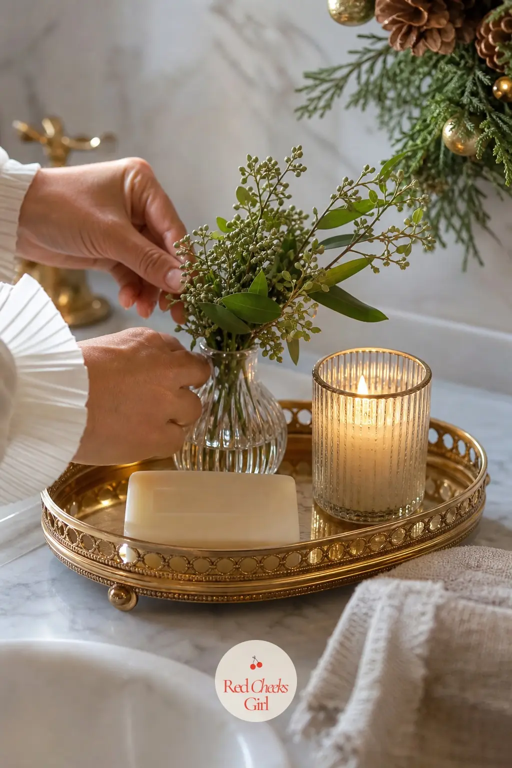 The Guest Bathroom Tray, Scented Like a Boutique — A small gilt tray by the sink holds a bar of milled soap, a scented candle, and a bud vase with one sprig of