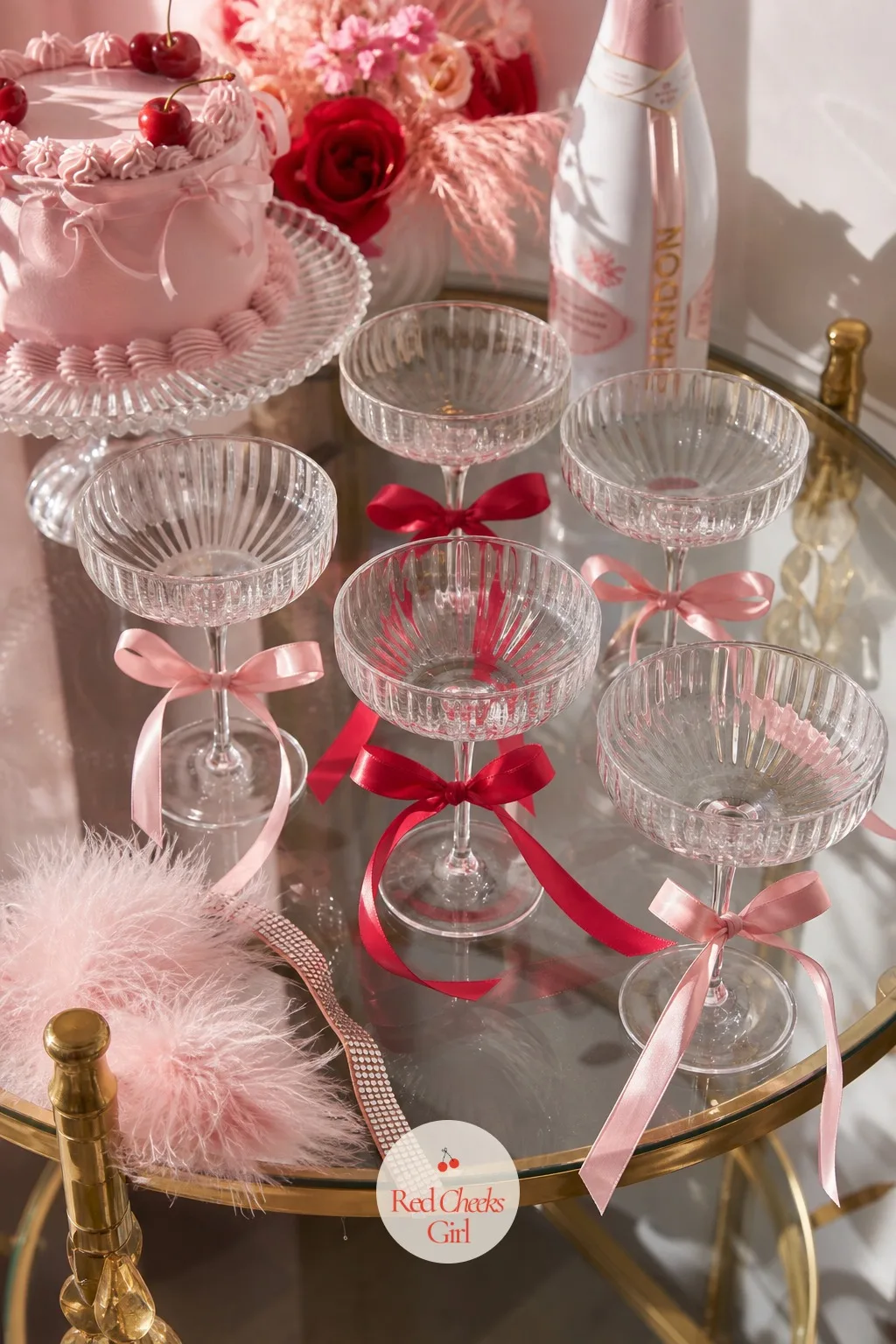 Coquette Bows Knotted Around Stemmed Glasses — A row of plain champagne glasses on a side table looks like it is waiting for the party to start. Galentines
