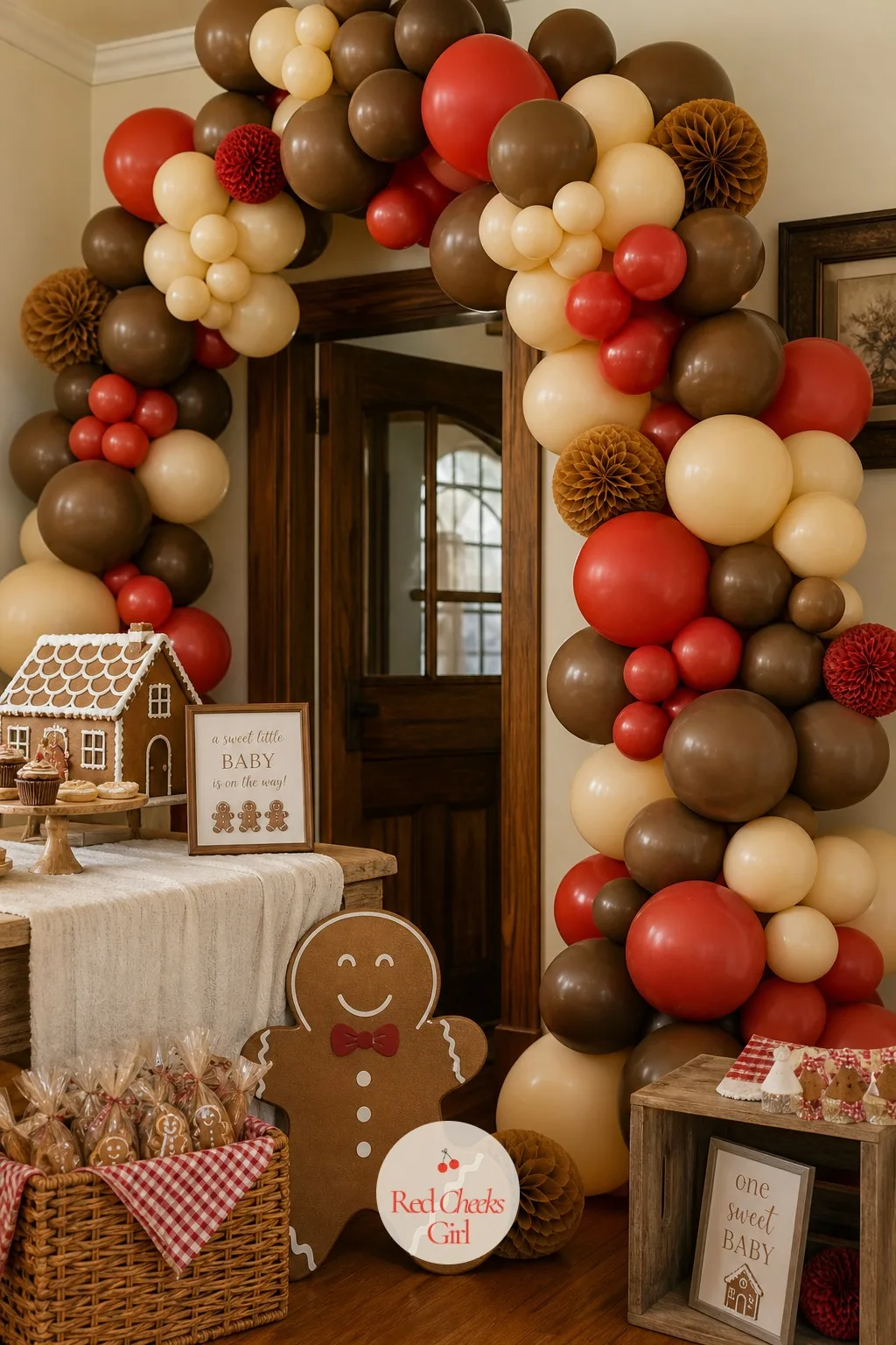 Gingerbread and Gumdrop Balloon Arch — An organic balloon arch builds in molasses brown, buttercream cream and cherry red, oversized tissue paper gumdrop