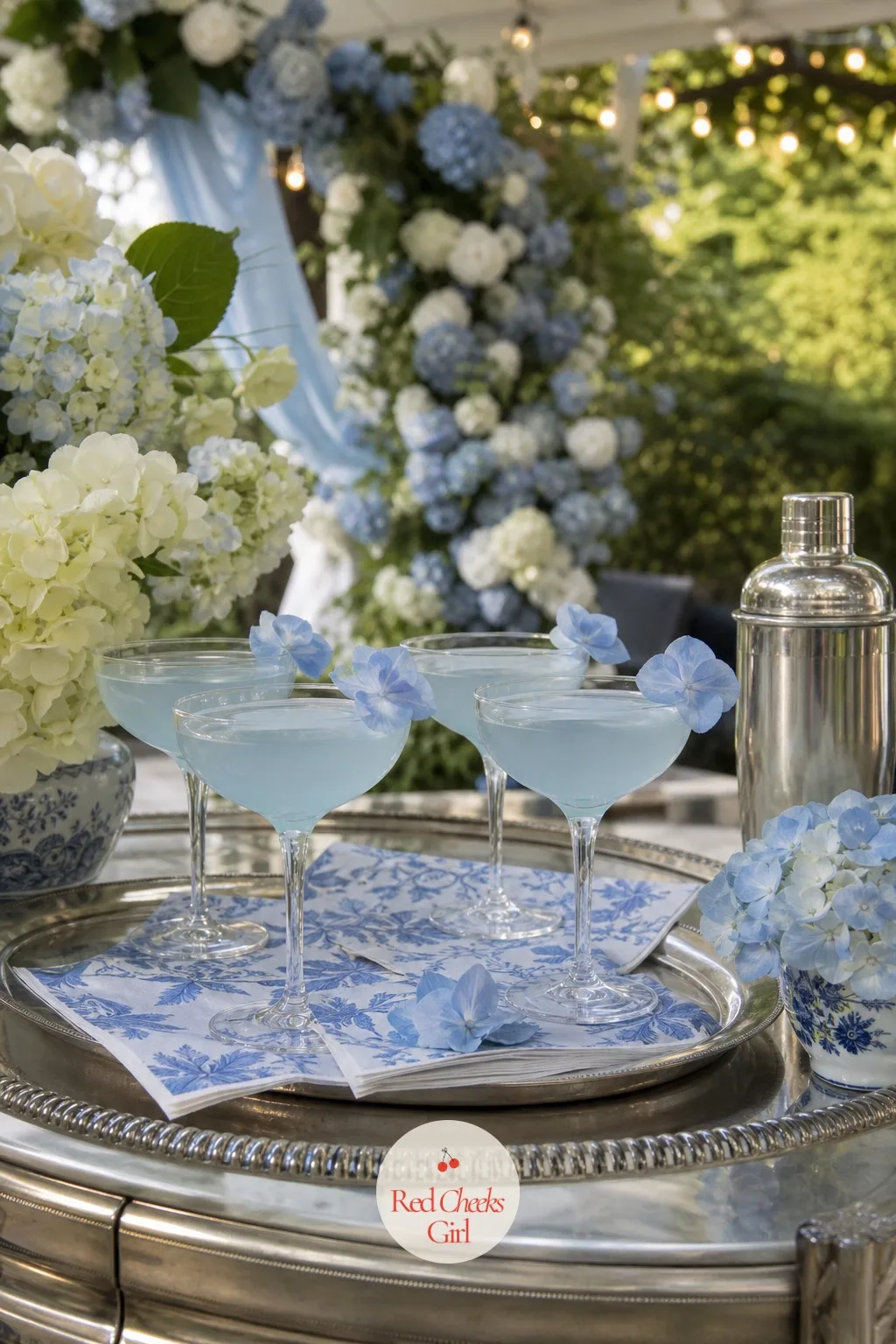 A Signature Cocktail Garnished with a Hydrangea Floret — A bar cart in the same colours gives guests a reason to linger near the dessert table instead of