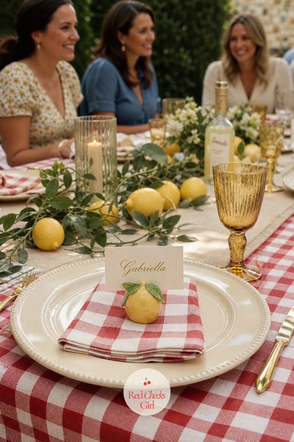 Lemon Place Cards — At each setting, a cream charger, a folded checked napkin, and a small lemon shaped holder pinching a place card with a name in gold