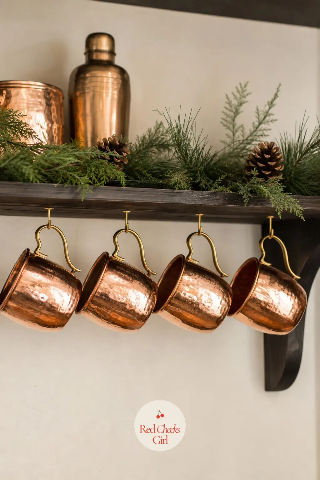 A Row of Copper Mugs Hung Beneath the Shelf — Hang four or five copper mugs from small hooks beneath an open kitchen shelf, handles facing the same direction.