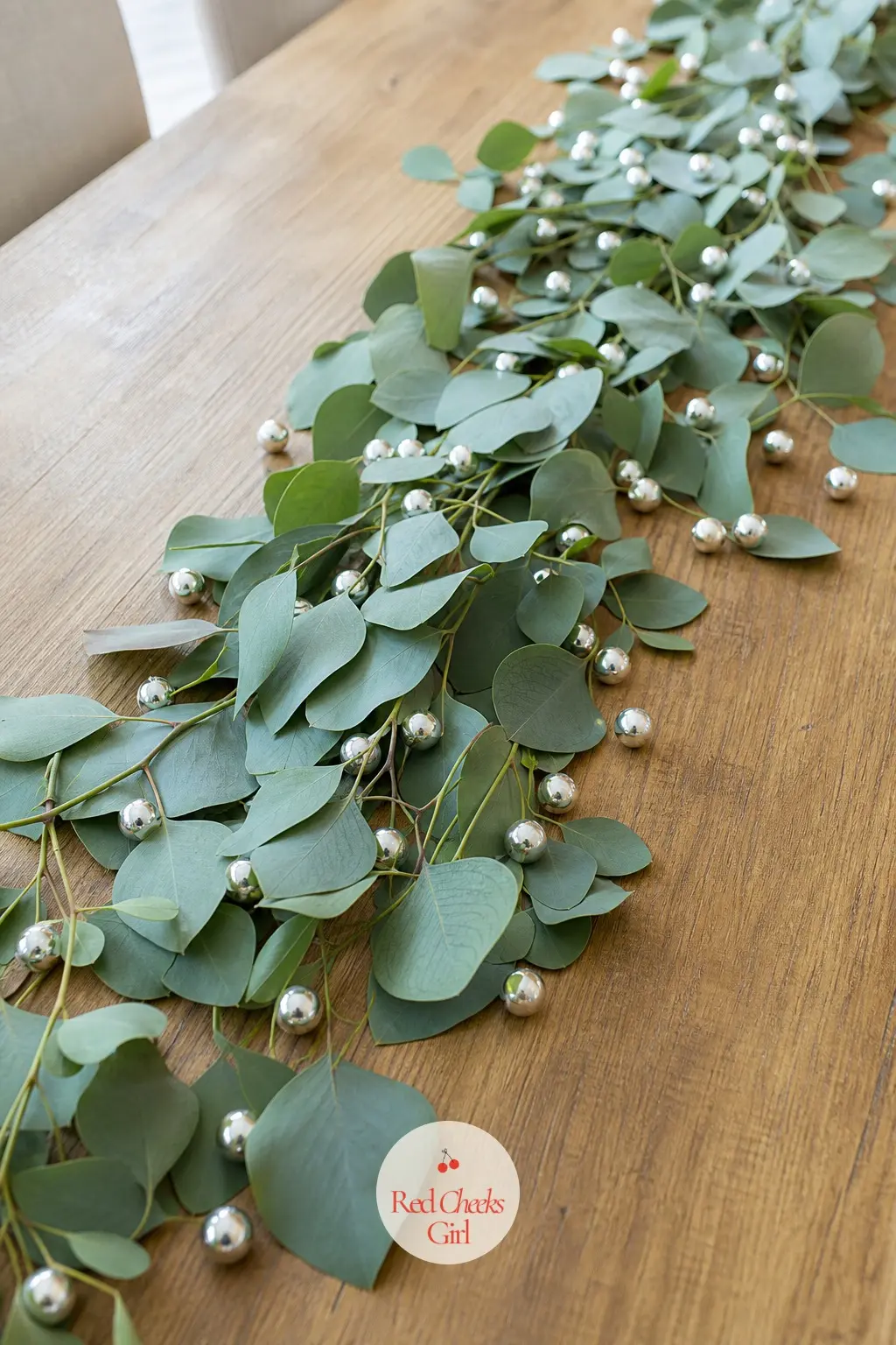A Runner of Eucalyptus and Silver Dragees Down the Table — Lay a loose runner of fresh eucalyptus stems straight down the center of the table, then scatter a