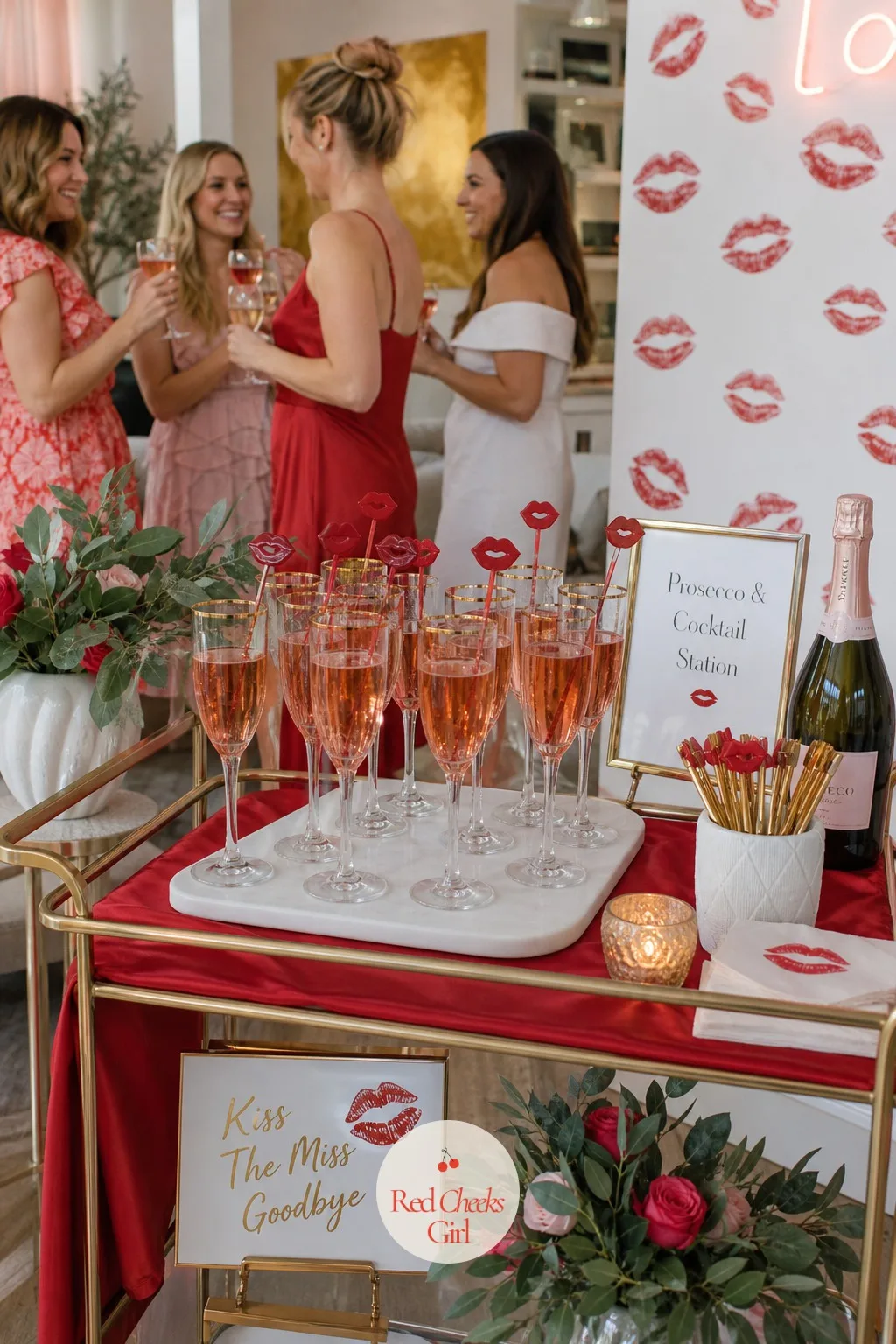 Prosecco and Cocktail Station With Lip Stirrers — Off to one side, a small bar cart or side table holds the drinks: prosecco in gold-rimmed glasses, a pitcher