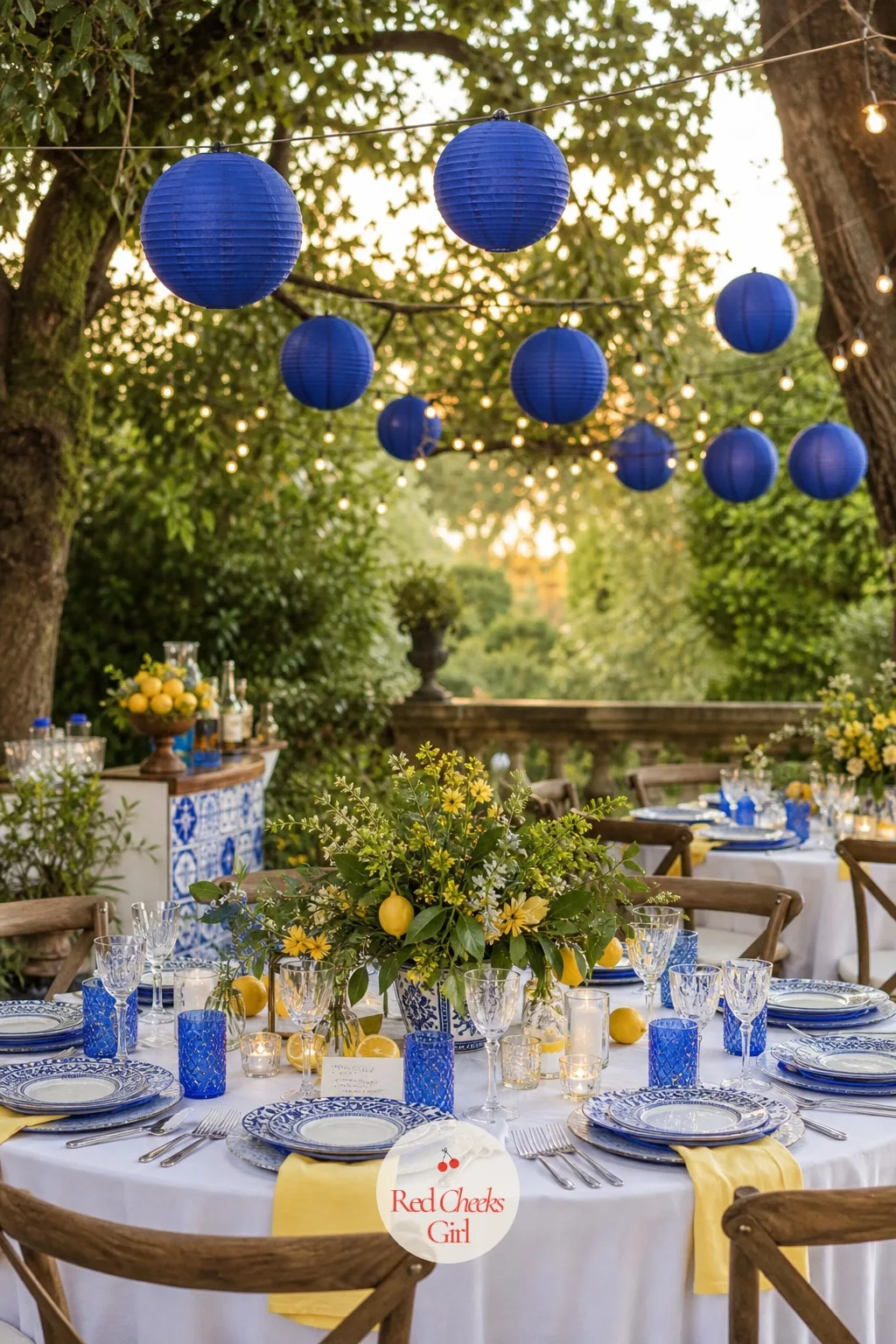 Blue Paper Lantern String Over the Patio — For a terrace or garden version of the day, the sky above the tables needs its own touch of cobalt once the sun