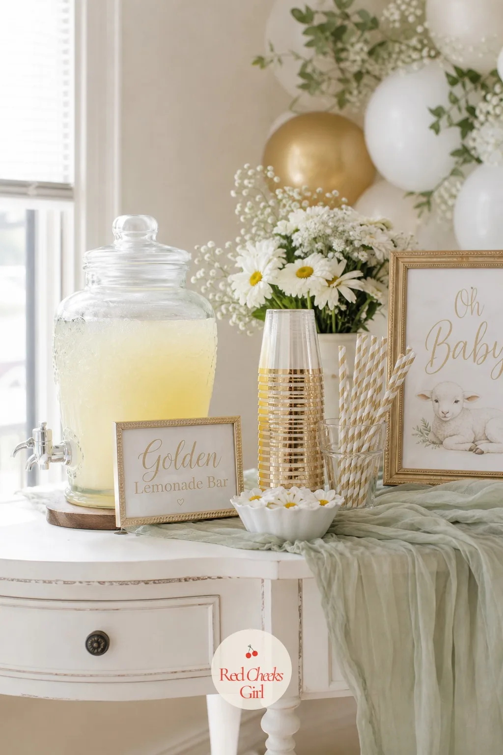 Golden Lemonade Bar — A glass beverage dispenser of fresh lemonade sits beside a stack of gold rimmed cups and striped paper straws in white and gold, with a