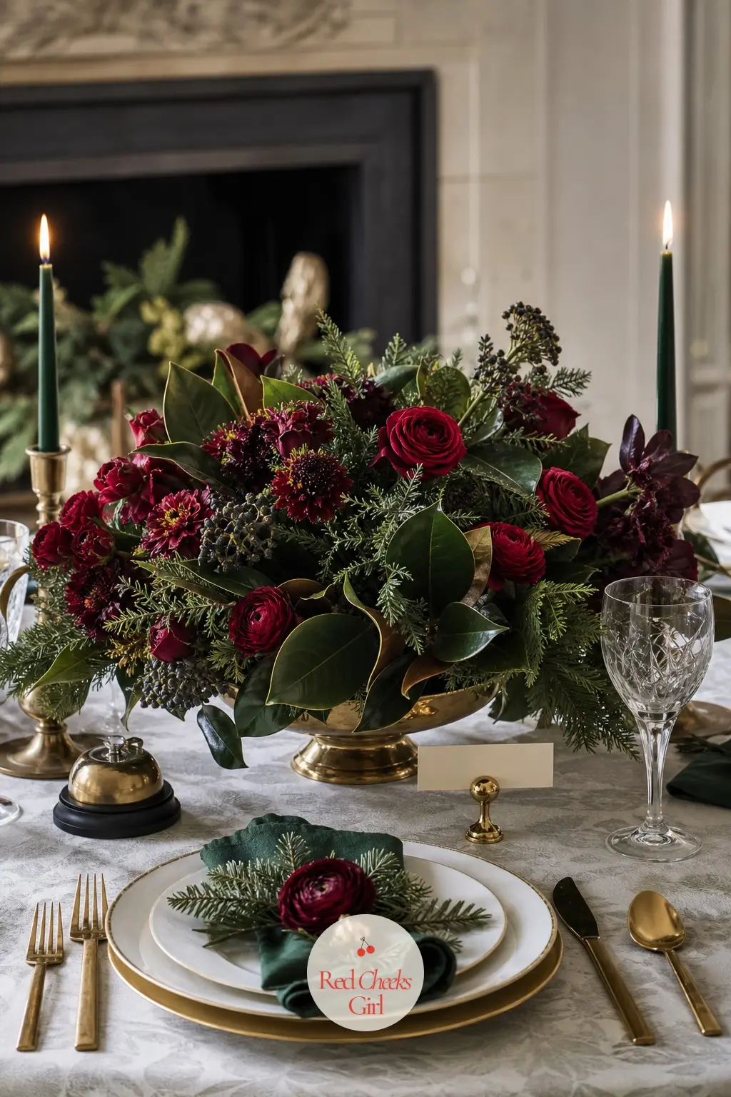 The Centrepiece and the Place Setting — Down the centre, a low arrangement of emerald foliage and bordeaux blooms in a brass bowl, kept low enough that guests