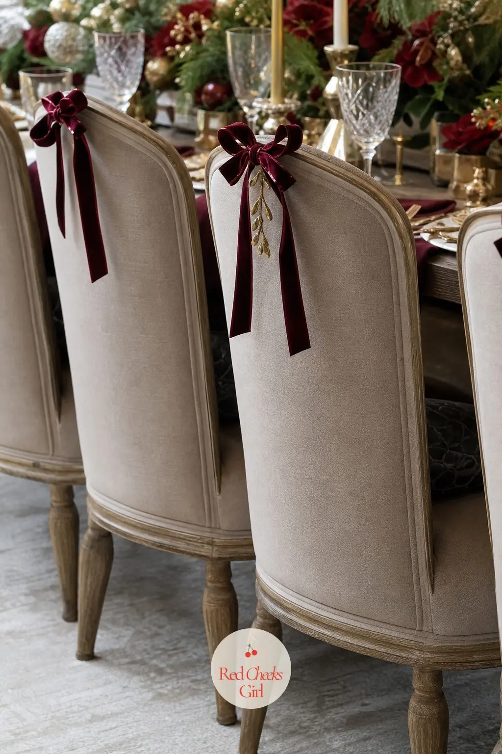 The Dining Chairs, Dressed at the Back — Each chair back takes a small bordeaux velvet bow tied high rather than a full bulky bauble, so the look reads from