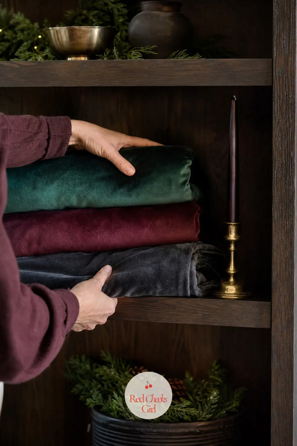 The Linen Shelf, Folded in Velvet — An open shelf or the top of a wardrobe in the guest room holds a stack of folded throws in the house's three colours, each