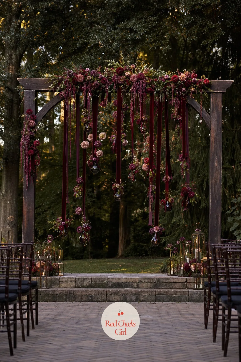 Hanging Florals With Dark Ribbon — A full floral arch can swallow a budget in one booking, and she knows it before the florist even opens the quote. Moody
