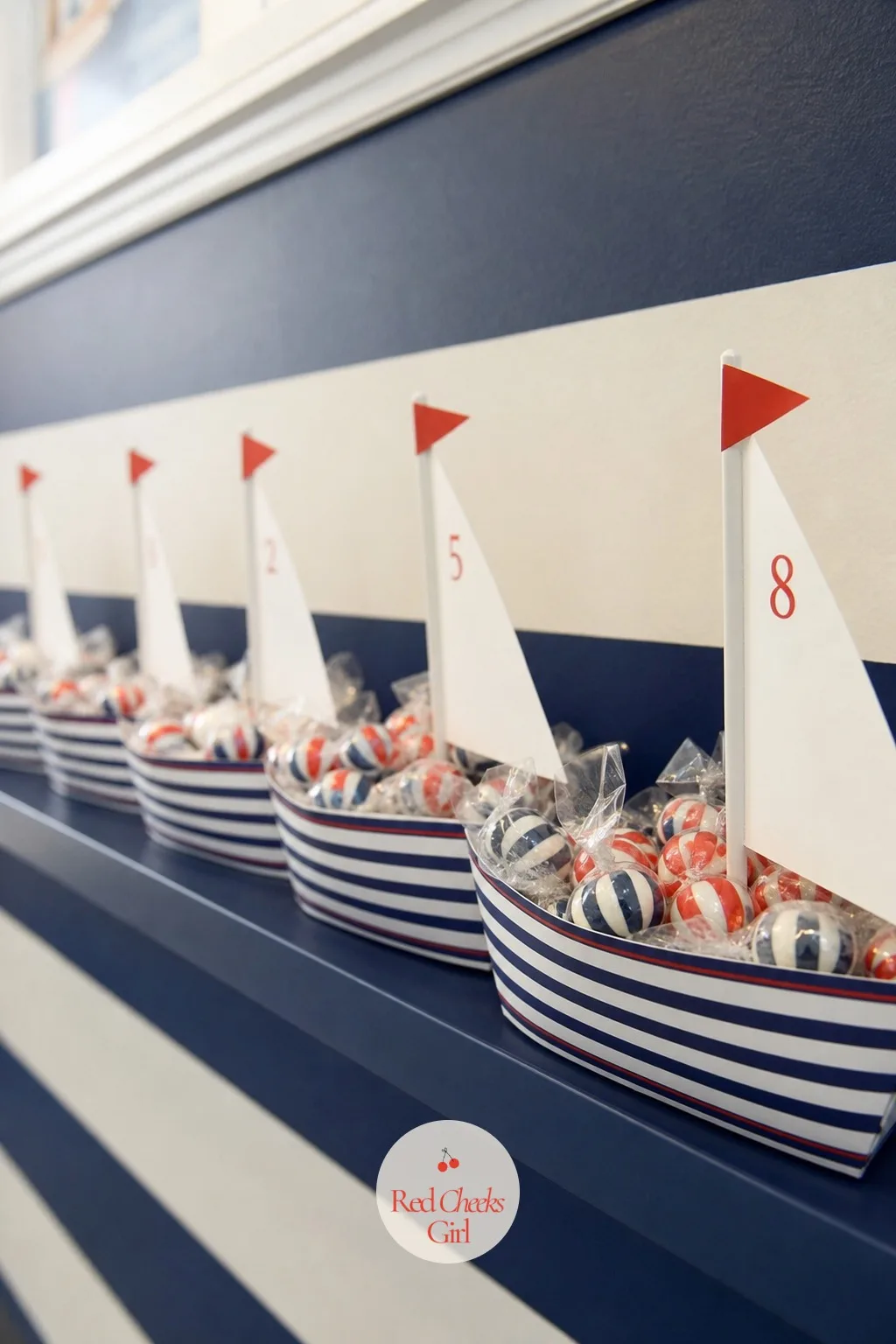 A Shelf of Paper Boat Favor Boxes — A single table of loose candy looks like an afterthought. Nautical birthday party