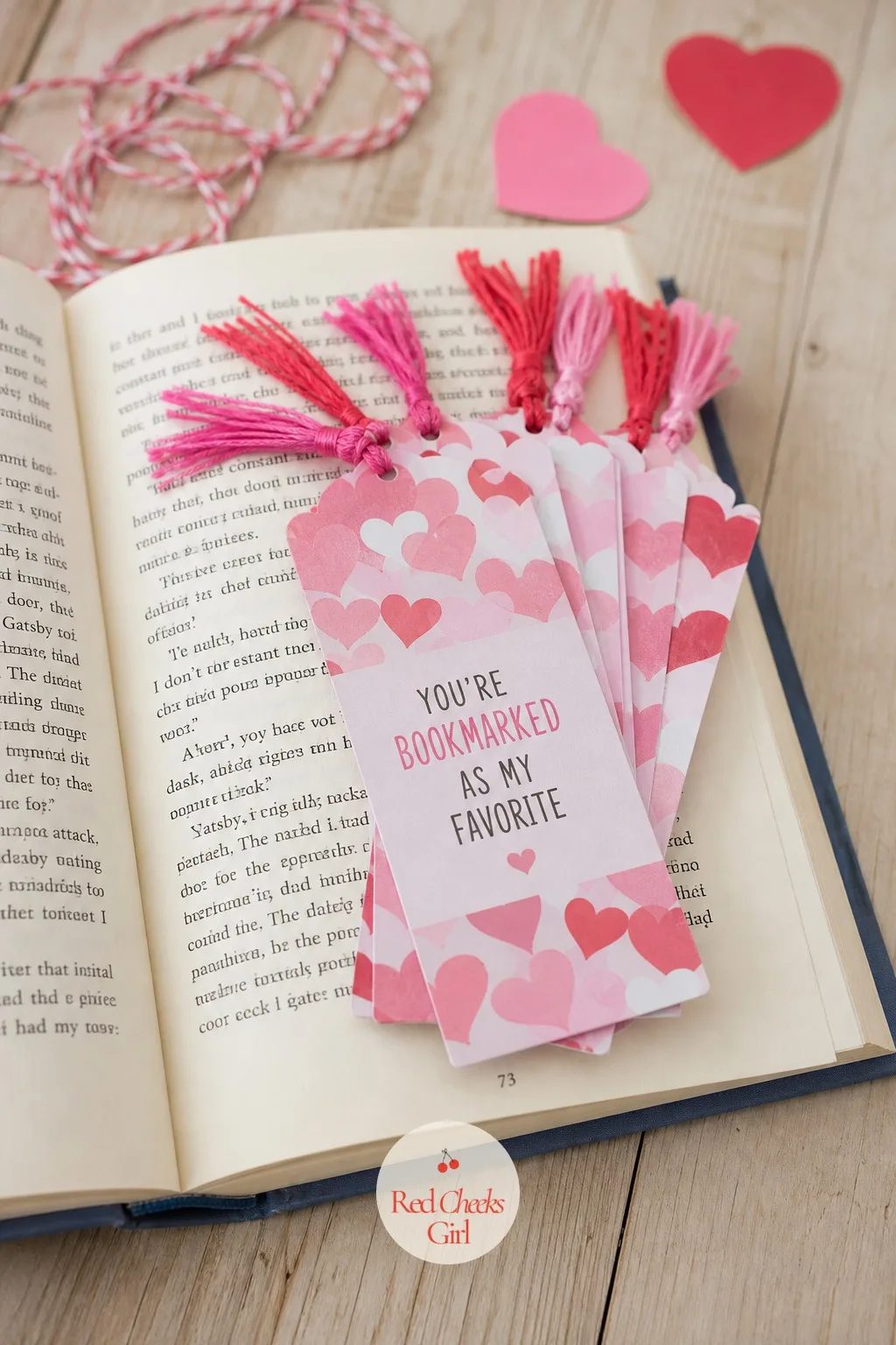Bookmarks: You're Bookmarked as My Favorite — A stack of small paper bookmarks, each with a short tassel knotted through a punched hole, lays across an open