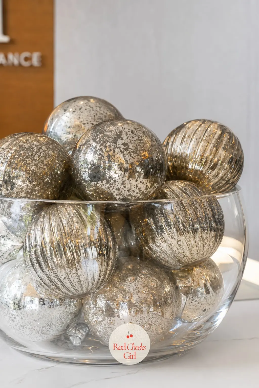 A Glass Bowl of Mercury Ornaments Anchoring the Reception Desk — One large glass bowl filled with silver and pewter mercury glass ornaments does more work than