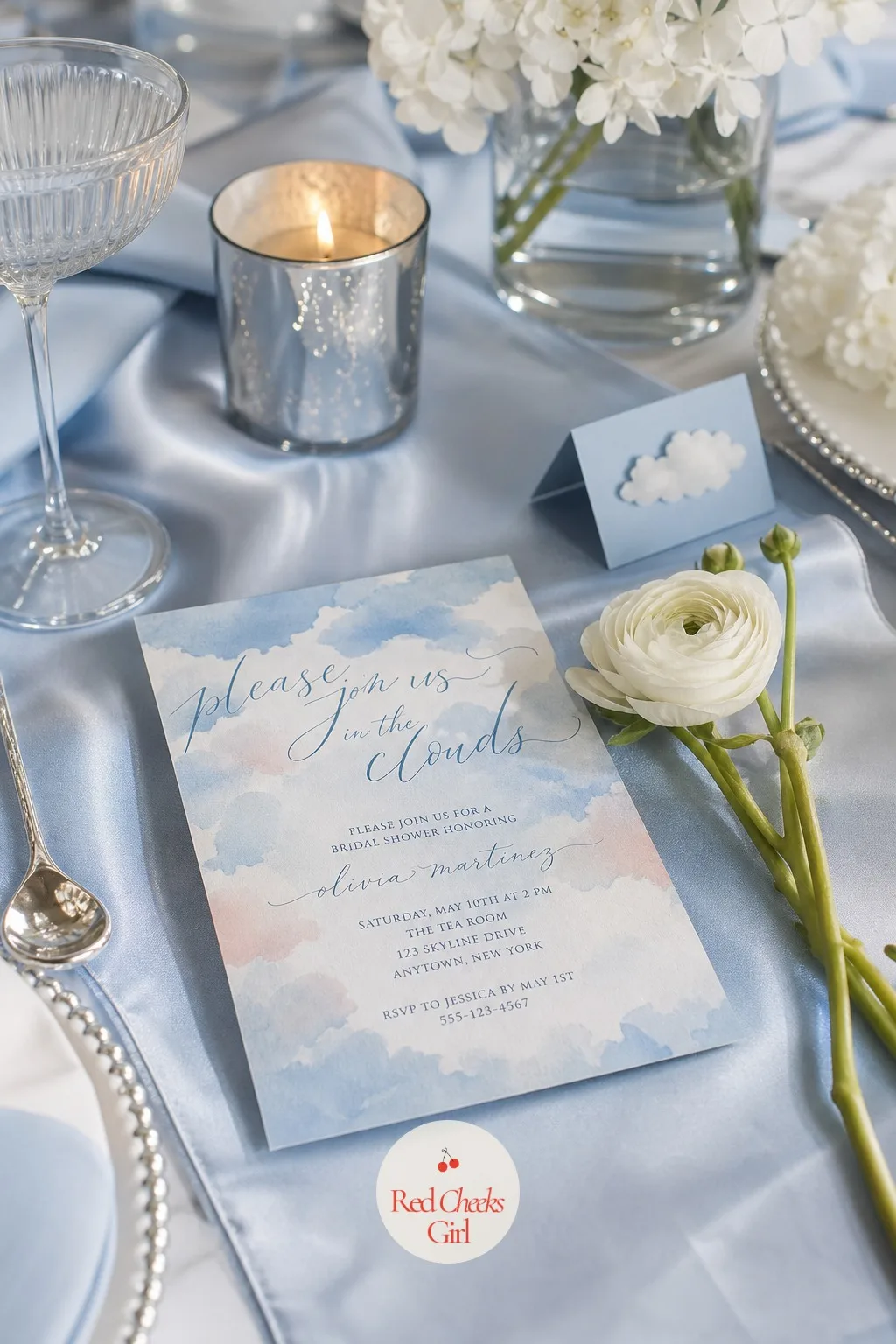 Invitation — Before anyone sees the balloon backdrop or tastes the cake, they see this: a card with a soft watercolor sky, pale clouds, and flowing script