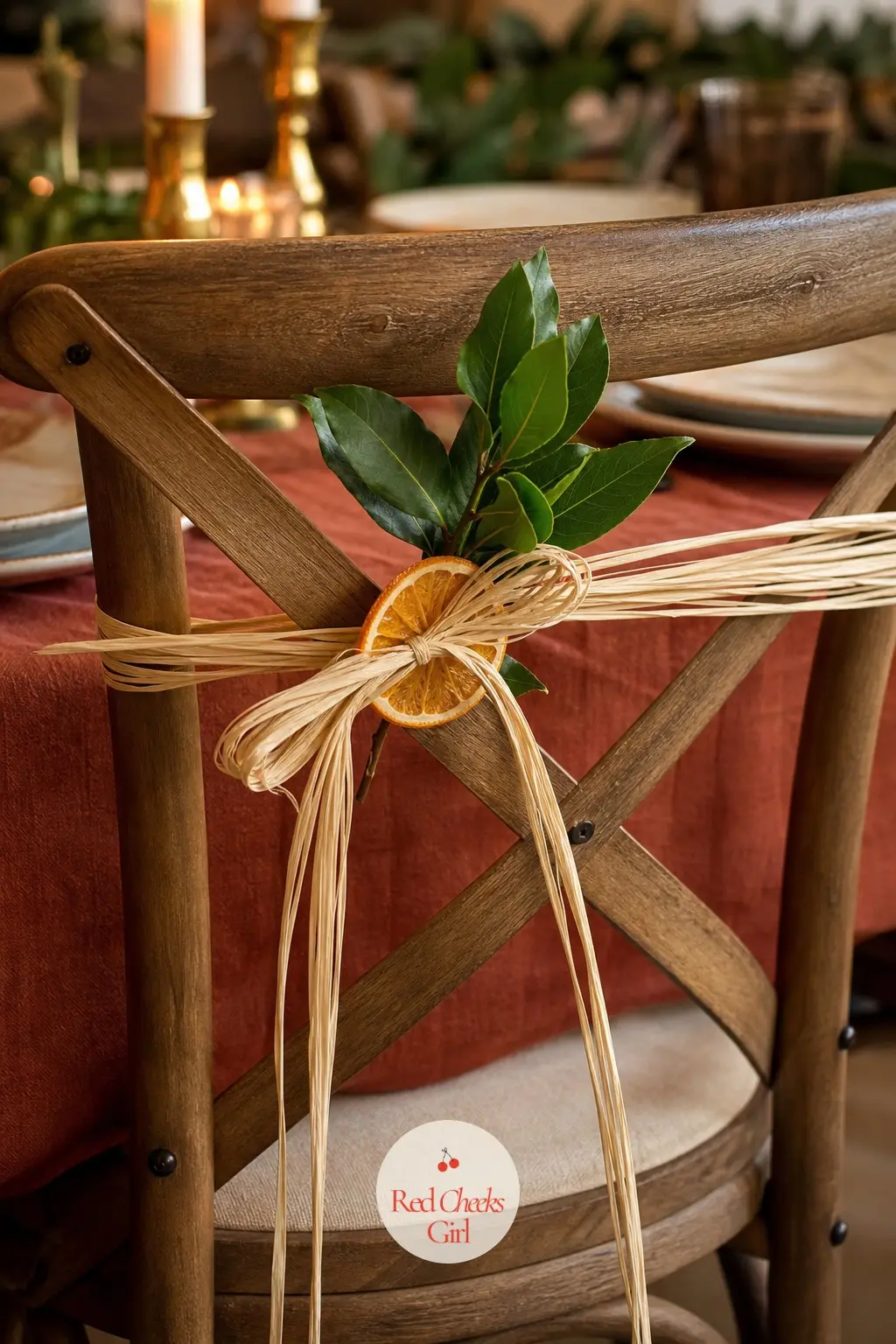 The Chair Backs, Tied with Raffia Bows and a Dried Orange Slice — Behind each chair, a raffia bow holds one dried orange slice against a sprig of fresh bay