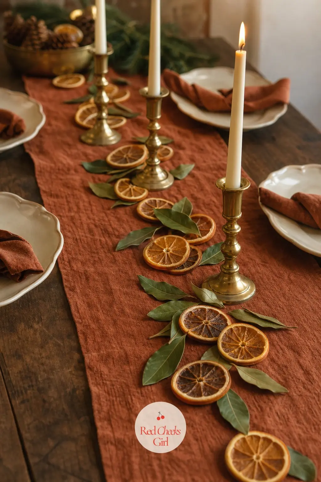 The Table Runner, Laid in Rust Linen with a Trail of Dried Orange Slices — A runner in rust linen lays the base colour down the table, with a loose trail of