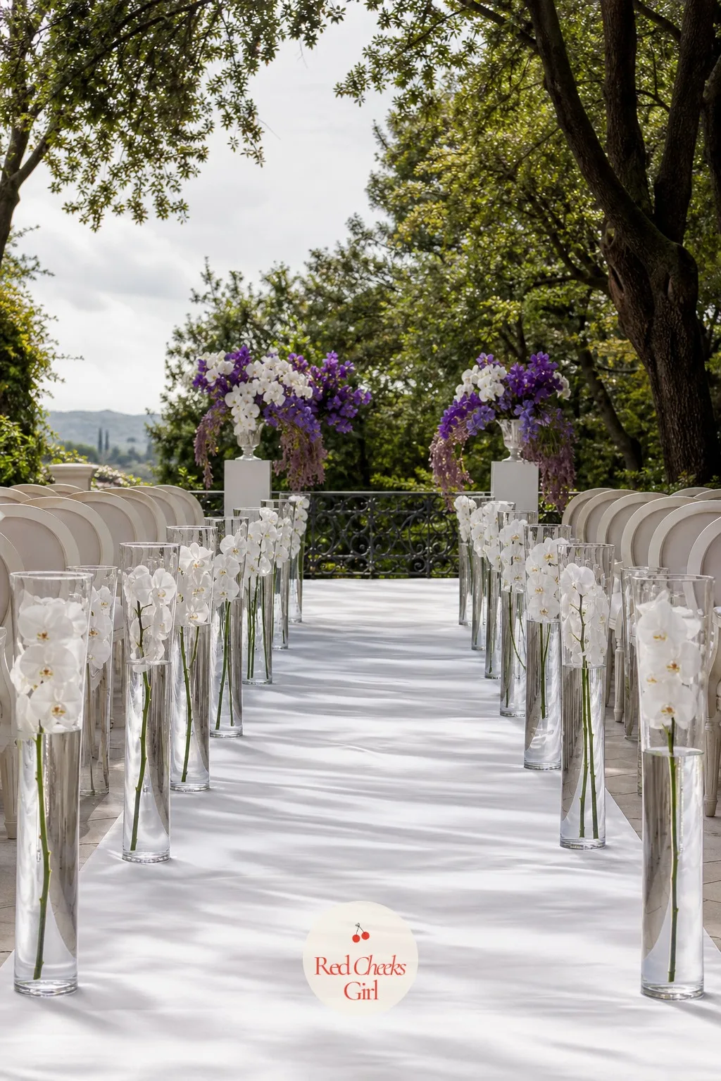 Aisle Lined with Tall Glass Vases of White Phalaenopsis — An empty aisle feels thin on camera, but she does not want to drag a full arrangement down every few