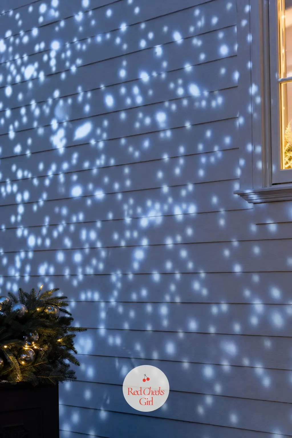 A Facade Washed in a Gentle Projector Snowfall Effect — A small projector aimed at the front facade casts a slow, soft snowfall of blue-white light across the