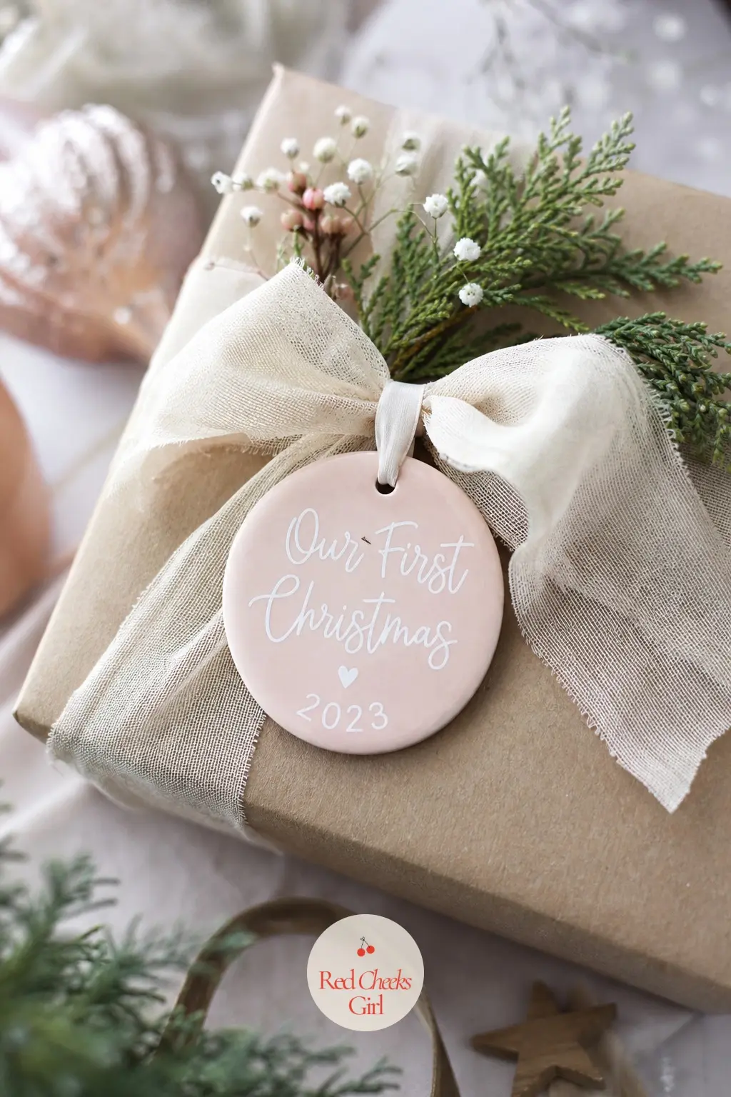 Our First Christmas Dated Ornament — The Our First Christmas Dated Ornament is painted blush pink with the words in white script and the year in gold beneath