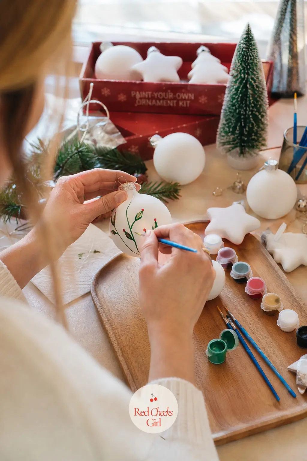 Paint-Your-Own Ornament Kit — The Paint-Your-Own Ornament Kit hands each guest a plain white blank, a tray of small paint pots and one brush, and lets the