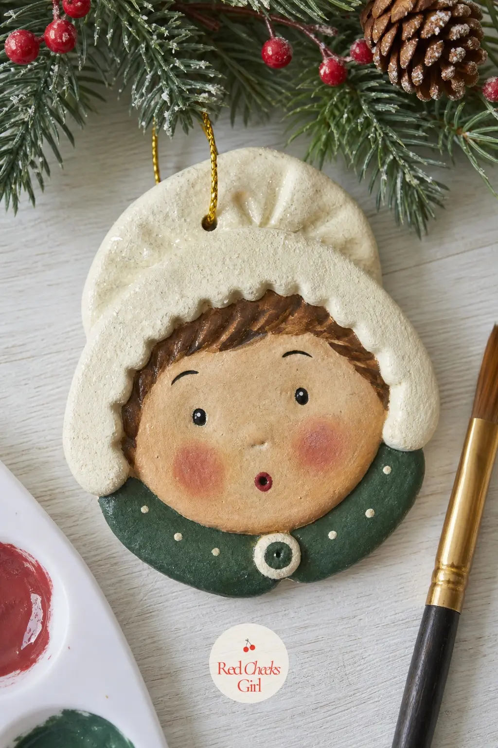 Caroler Girl Face Ornament — A cream bonnet shape painted around the top and sides of the face frames it like a hood, leaving just the centre free for