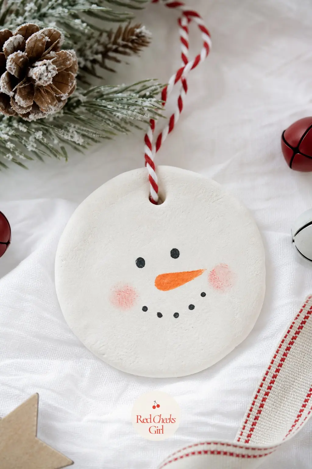 Snowman Face Ornament — White dough rolled into a plain round is the whole base, and everything else comes from the brush: a small orange triangle for the