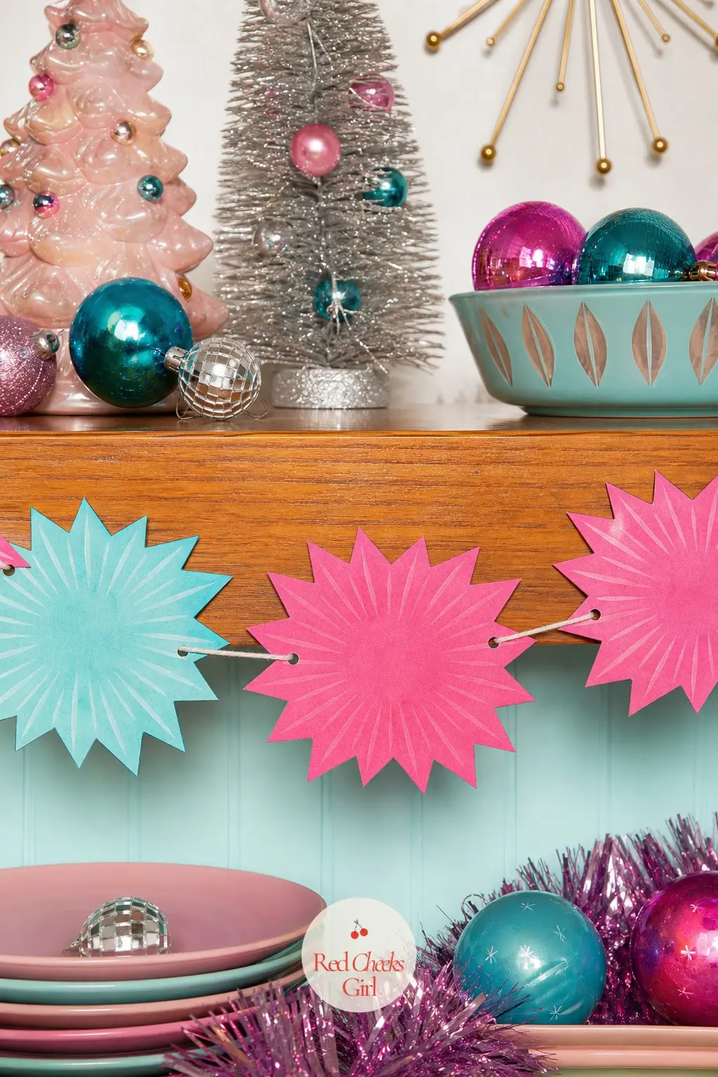 Atomic Starbursts Paper Chain — Starburst shapes in turquoise and pink, each with thin radiating lines drawn across it, strung flat on string rather than