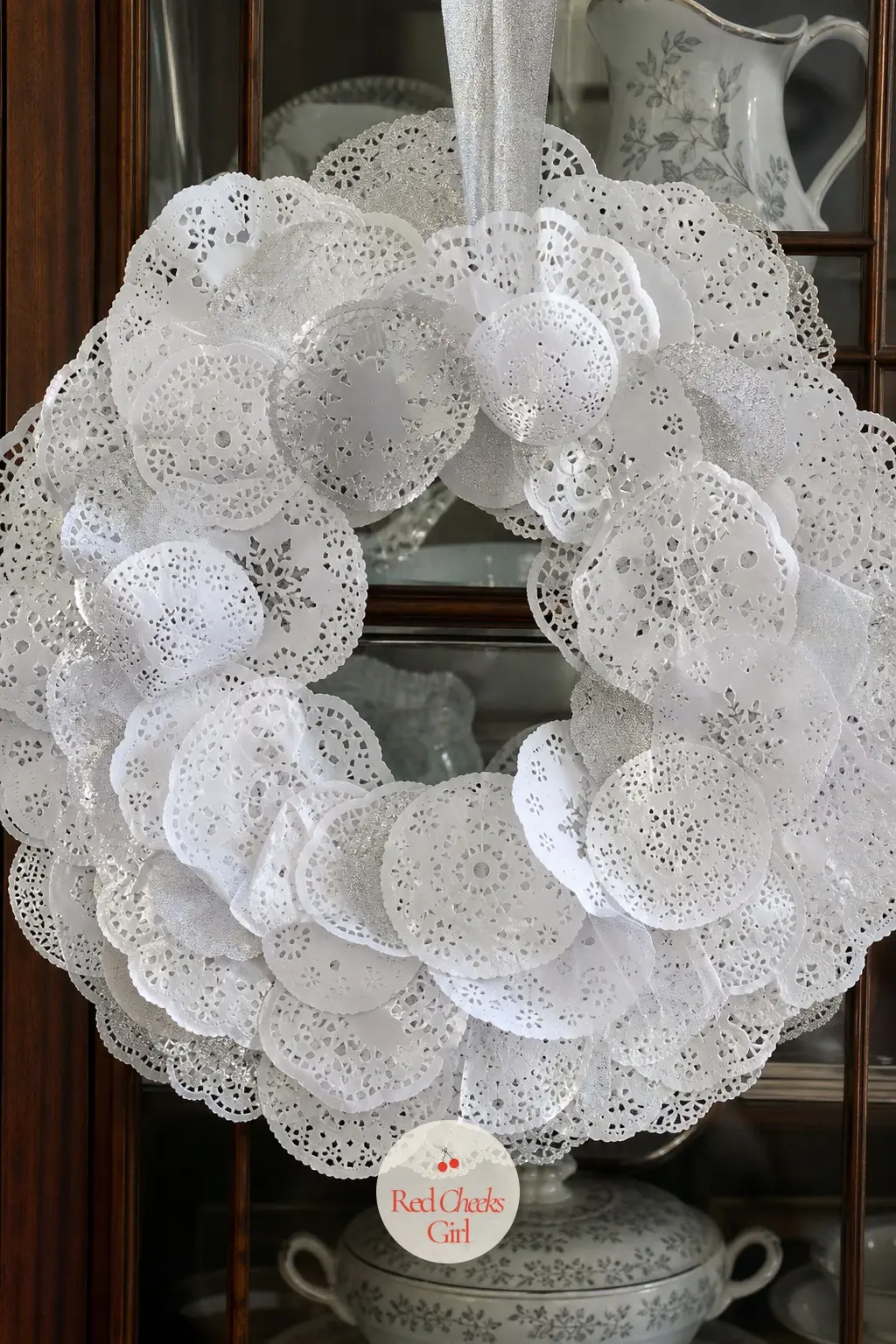 The Silver and White Punched Lace Snowflake Wreath for the China Cabinet — Small punched paper rounds, silver behind white, stack three deep so light passes