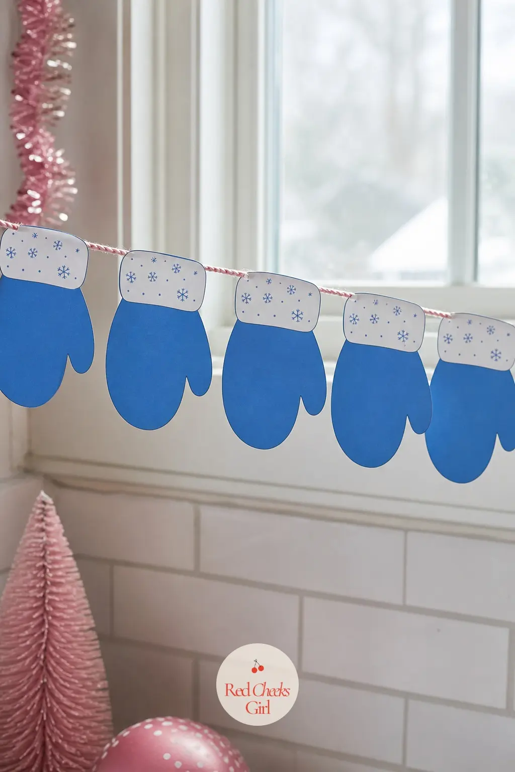 Blue Mittens — A simple mitten shape in medium blue with a white cuff dotted in tiny snowflakes, repeated identically down the string rather than paired left