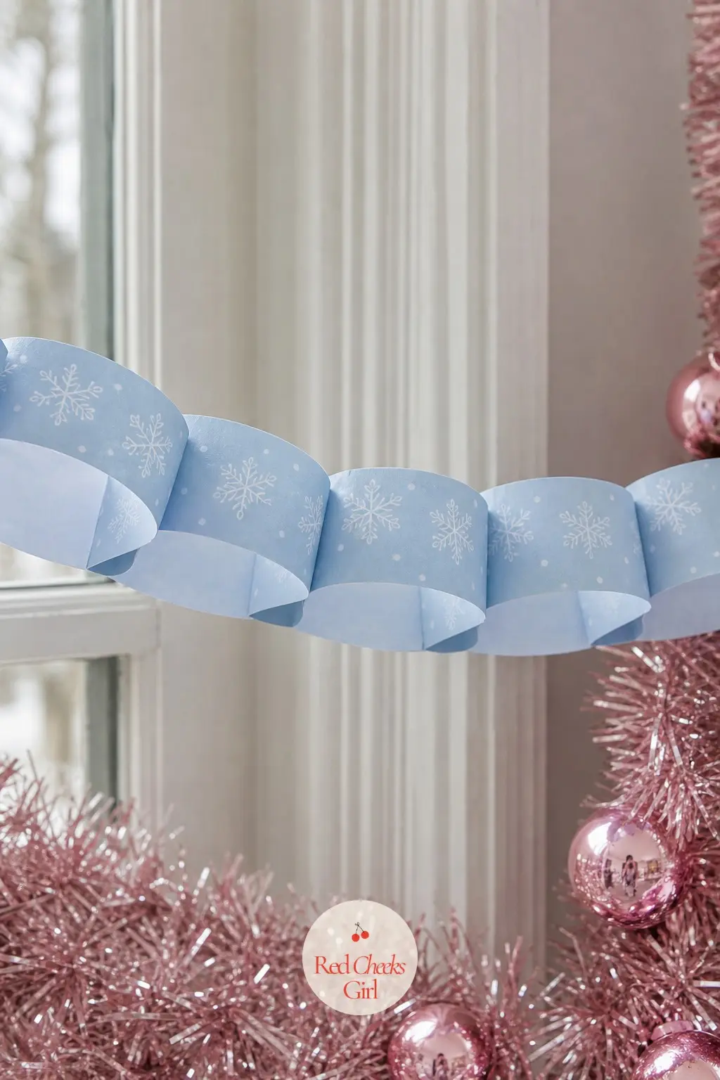 White Snowflakes — A paper chain again, this time each strip carrying a row of small white snowflake outlines on a pale ice-blue ground, so the chain reads as
