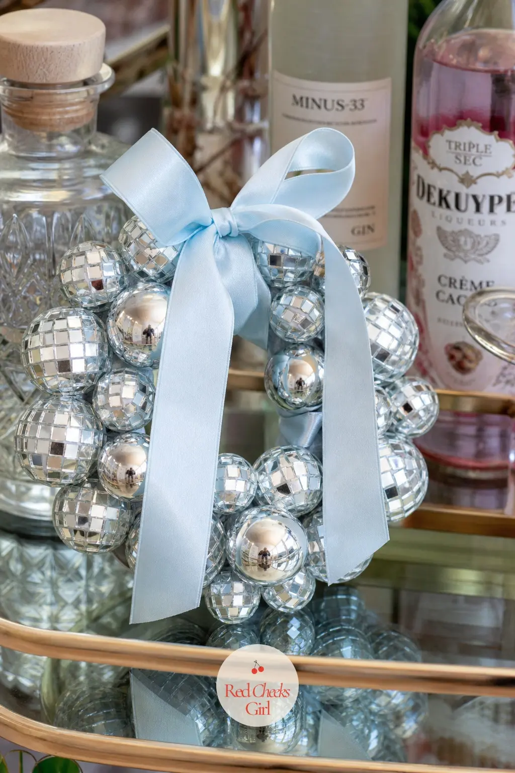 The Icy Blue Satin Ribbon and Mirrored Bauble Wreath for the Home Bar Cart — Pale icy blue satin ribbon weaves through a cluster of mirrored baubles in two