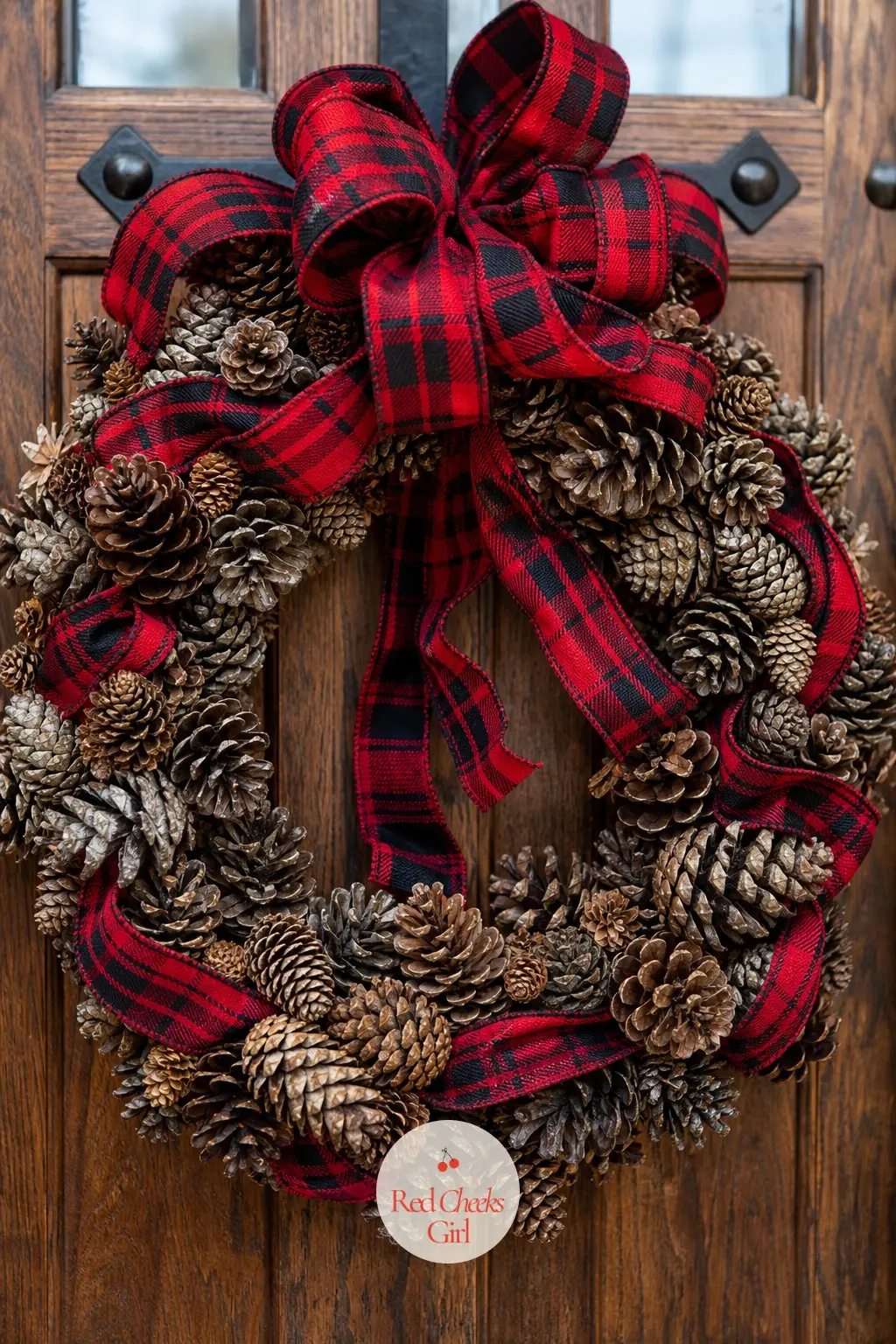 The Red Plaid Ribbon and Pinecone Wreath for the Ski Chalet Entry — A thick red and black plaid ribbon loops twice around a wreath built mostly from natural