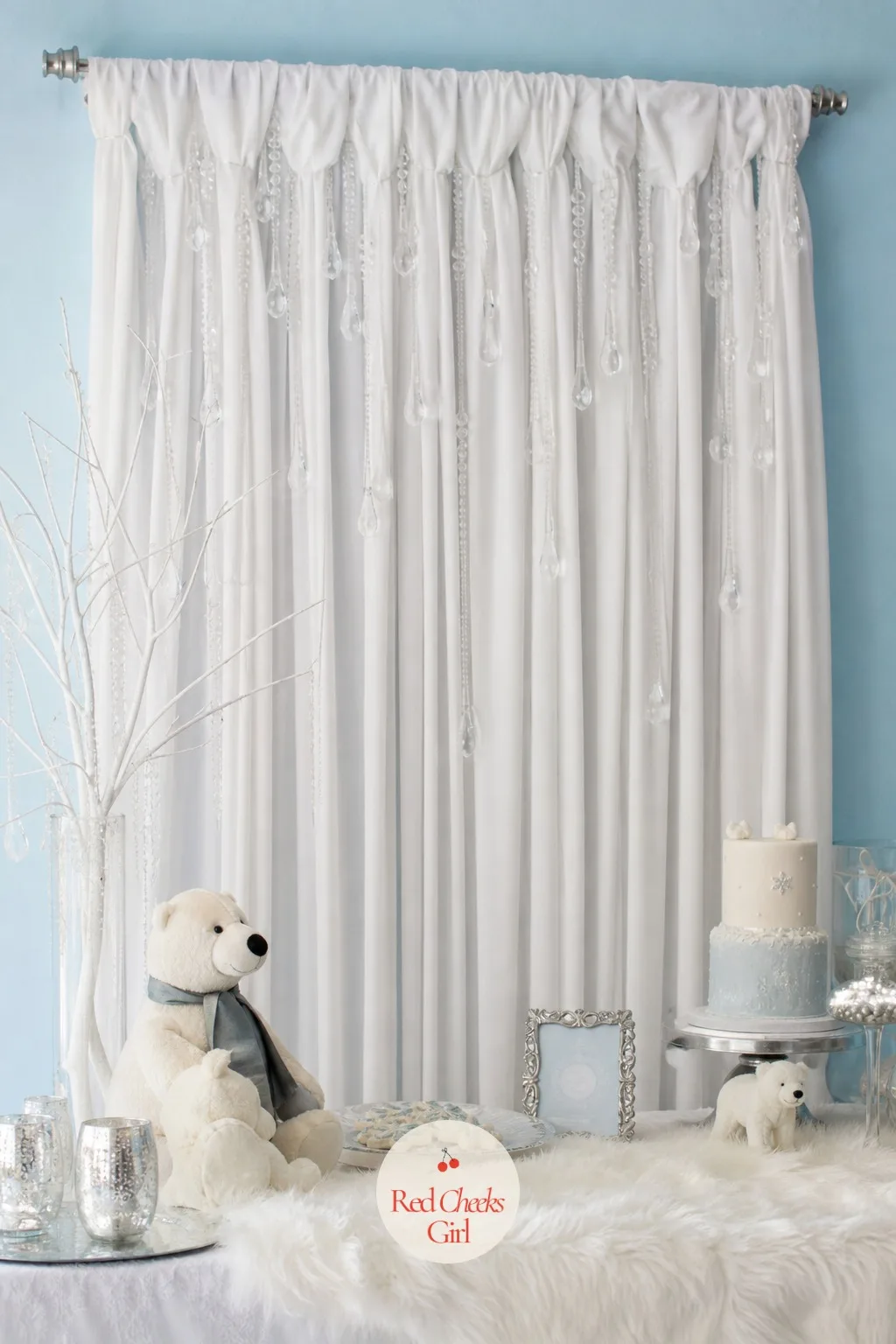 Fabric Icicle Backdrop — Lengths of white fabric drape from a curtain rod in soft folds, with clear acrylic icicle drops hung at staggered heights so they