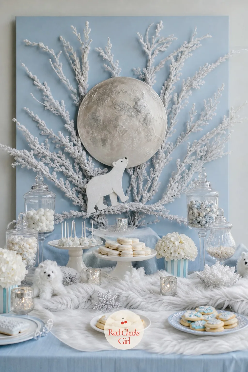 Frosted Branch Backdrop with a Painted Moon — Bare branches, flocked white at the tips, fan out across a plain backdrop panel behind the main table, with a